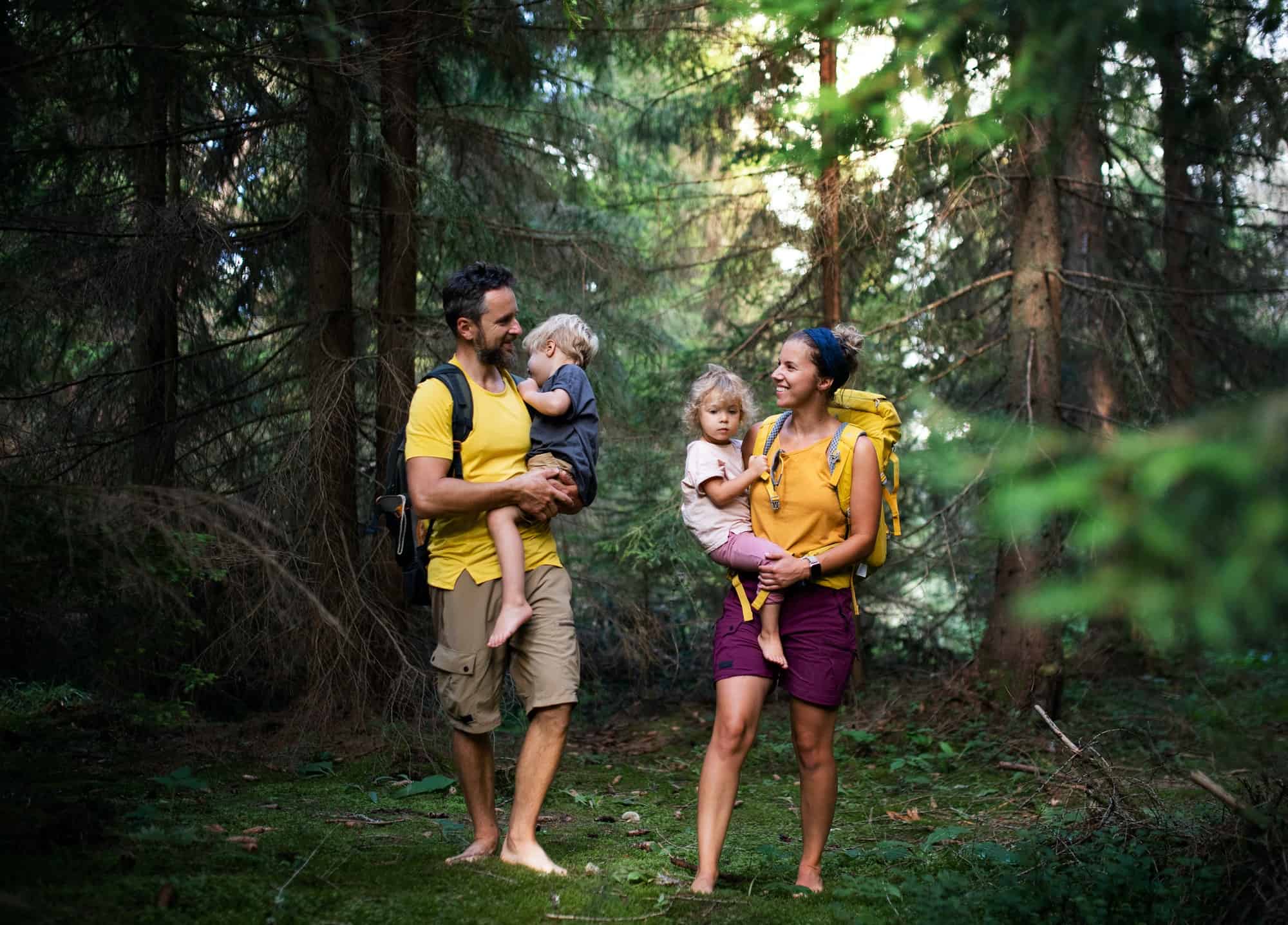 Family with small children walking barefoot outdoors in summer nature