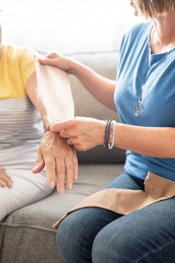 A cancer rehabilitation physiotherapist holding a compression sleeve next to a client’s arm who is dealing with lymphedema.