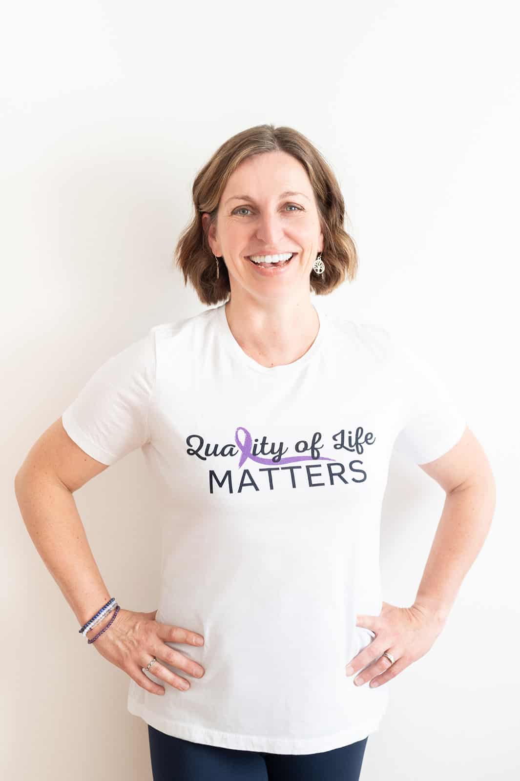 Beth Hoag, cancer rehabilitation physiotherapist, standing and wearing a white t-shirt that says “Quality of Life Matters.”
