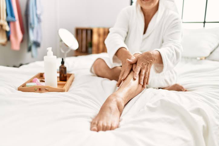 Woman applying lotion to her leg, an area that is at risk of developing Cellulitis.