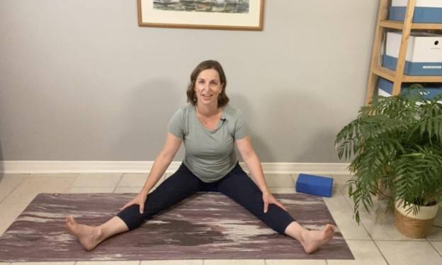 Beth Hoag, Physiotherapist, on the floor with her legs straight out in a v position a beneficial hip and low back stretch after pelvic radiation therapy.