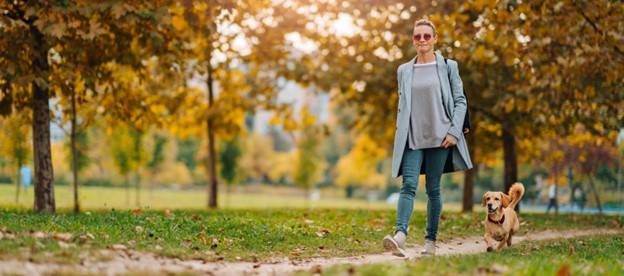 Woman outside walking her dog to reduce stiffness in her hips and low back due to Pelvic Radiation Therapy