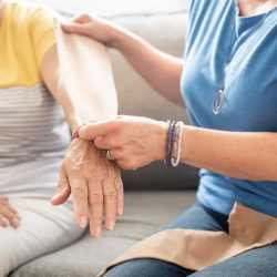 A cancer rehabilitation physiotherapist holding a compression sleeve next to a client’s arm who is dealing with lymphedema.